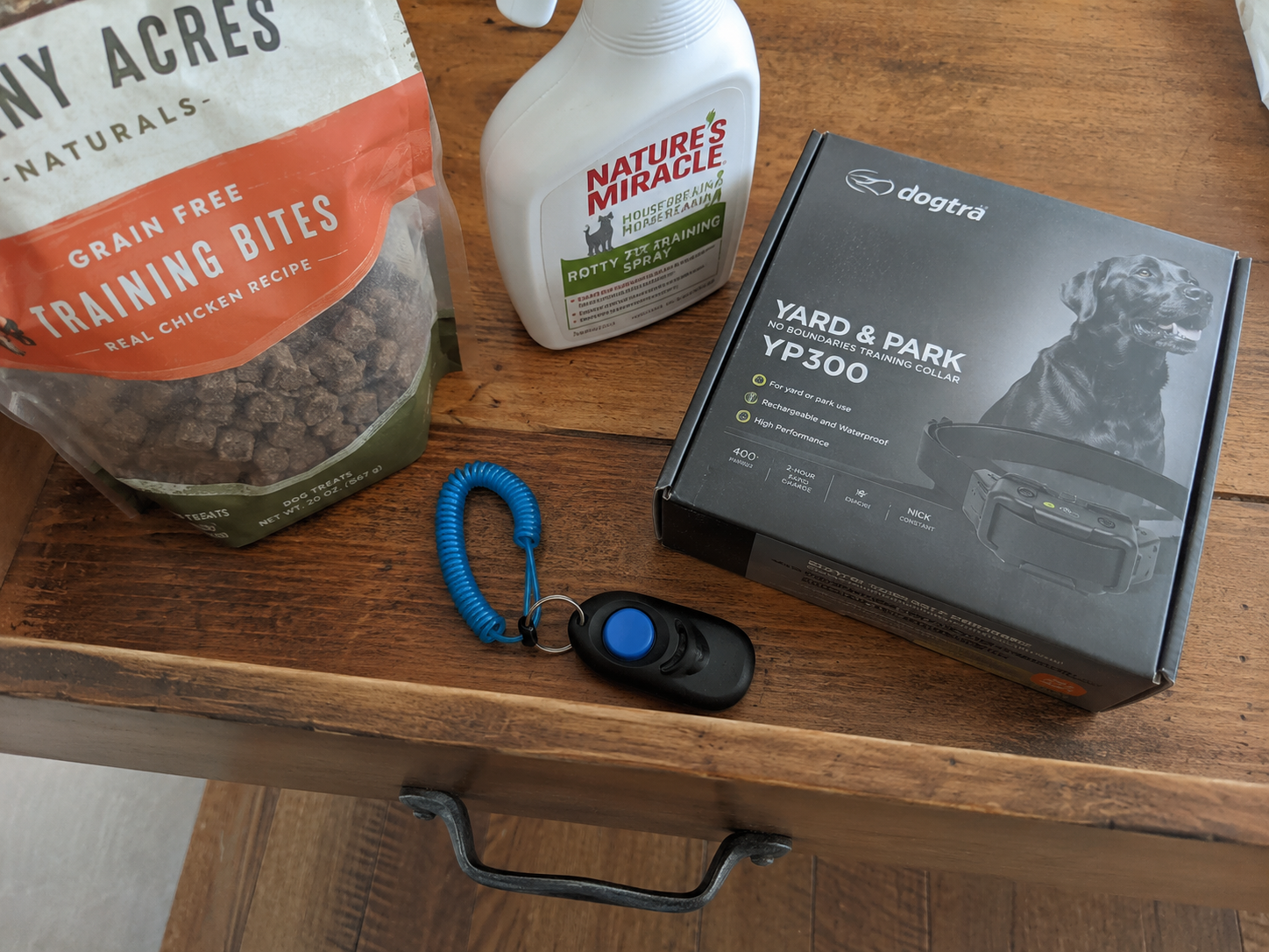 Flat-lay of training tools that didn't work: clicker, spray bottle, treat bag, and an unopened shock collar box